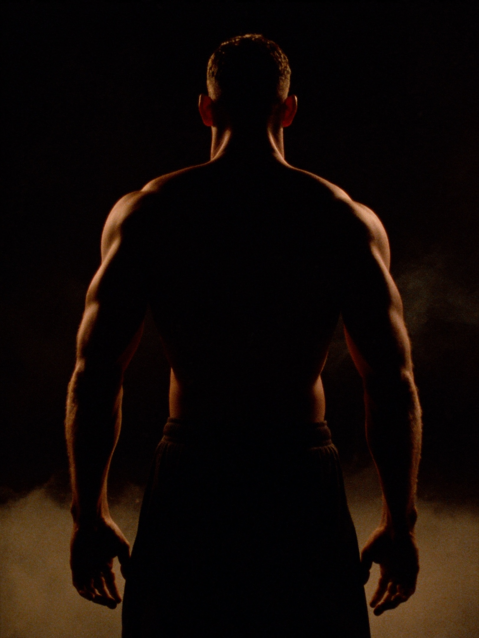 Athlete's back in chalk dust and amber light